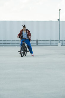 Boy with BMX bike and headphones on parking level - UUF000814