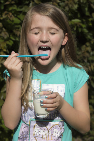 Porträt eines Mädchens, das Milch aus einem Trinkhalm leckt, lizenzfreies Stockfoto