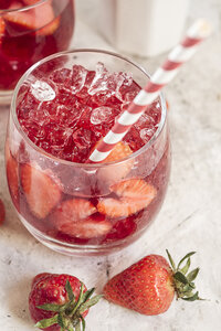 Ein Glas geeister roter Früchtetee mit geschnittenen Erdbeeren und zerstoßenem Eis - SBDF000976