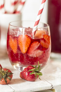 Ein Glas geeister roter Früchtetee mit geschnittenen Erdbeeren und zerstoßenem Eis - SBDF000981