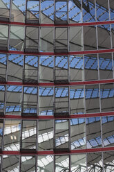 Deutschland, Berlin, Dachkonstruktionen spiegeln sich in der abgerundeten Glas- und Stahlfassade eines Bürogebäudes - ZMF000286