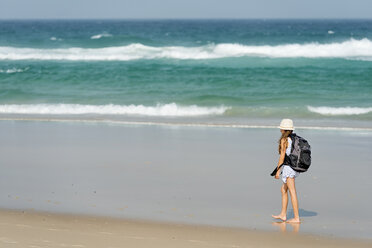 Australien, New South Wales, Pottsville, Mädchen mit Rucksack läuft am Strand - SHF001372