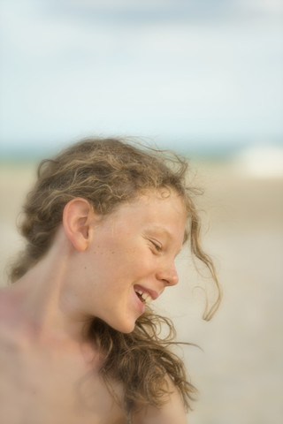 Australien, New South Wales, Pottsville, lächelnder Junge mit langen Haaren am Strand, lizenzfreies Stockfoto