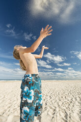 Australien, New South Wales, Pottsville, Junge am Strand wirft Sand in die Luft - SHF001362