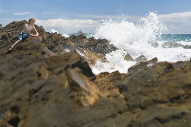 Australien, New South Wales, Byron Bay, Broken Head Naturschutzgebiet, Junge auf Felsen mit brechenden Wellen im Vordergrund - SHF001344