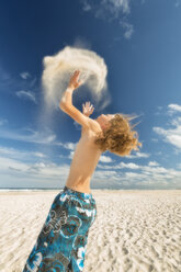 Australien, New South Wales, Pottsville, Junge am Strand wirft Sand in die Luft - SHF001345