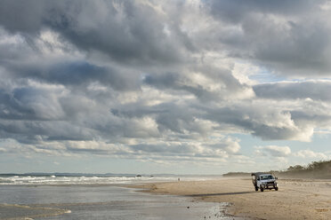 Australien, New South Wales, Pottsville, Geländewagen steht am Strand mit Brandung und dunklen Wolken - SHF001402