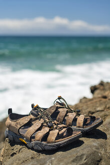 Australien, New South Wales, Byron Bay, Broken Head Naturschutzgebiet, Trekkingsandalen auf Felsen mit brechenden Wellen dahinter - SHF001378