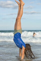 Australien, New South Wales, Pottsville, Mädchen macht einen Handstand im Ozean - SHF001403