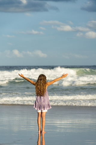 Australien, New South Wales, Pottsville, Mädchen mit langen Haaren am Meer mit ausgestreckten Armen, lizenzfreies Stockfoto