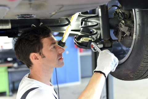 Automechaniker in einer Werkstatt bei der Arbeit am Auto, lizenzfreies Stockfoto