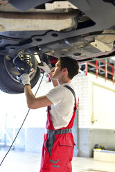 Automechaniker in einer Werkstatt bei der Arbeit am Auto - LYF000050