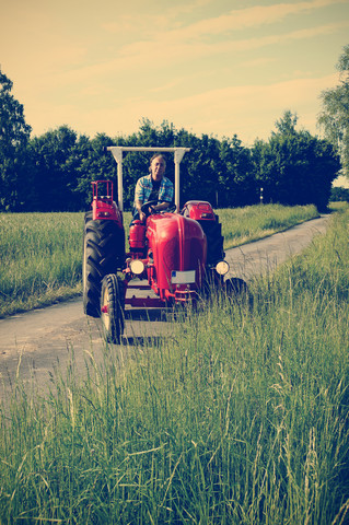 Germany, North Rhine-Westphalia, Minden, Oldtimer Porsche, Man driving an old tractor stock photo