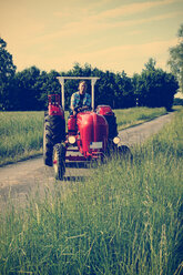 Germany, North Rhine-Westphalia, Minden, Oldtimer Porsche, Man driving an old tractor - HOHF000869