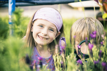 Brother and sister watching flowers with magnifying glass - SARF000671