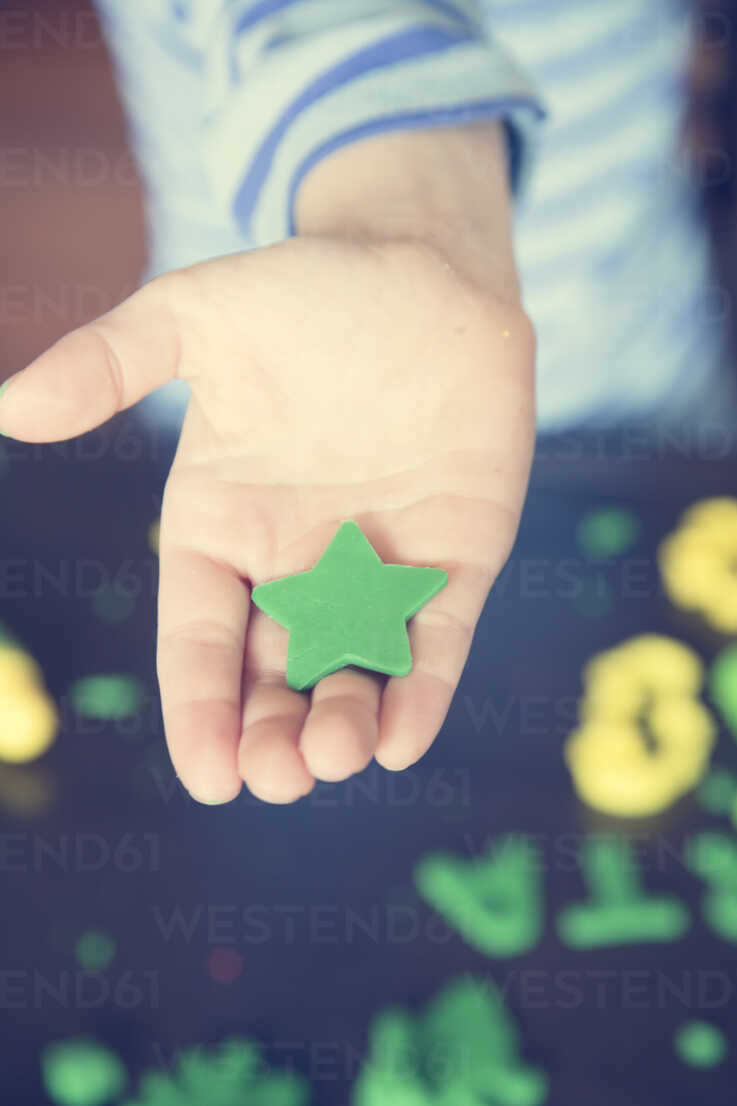 Green star shaped from modeling clay on little girl's palm stock photo