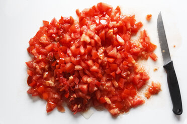 Diced tomatoes and kitchen knife on white ground - EVGF000623