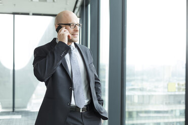 Businessman in office on cell phone - WESTF019474