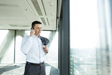 Businessman in office on cell phone - WESTF019477