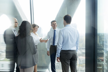 Businesspeople in office with woman using digital tablet - WEST019276