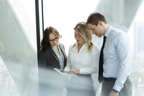 Businesspeople in office with woman using digital tablet - WEST019481