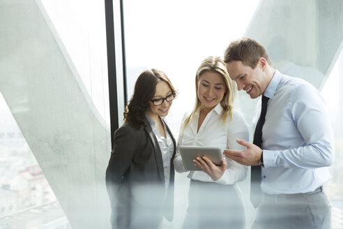 Businesspeople in office with woman using digital tablet - WESTF019482