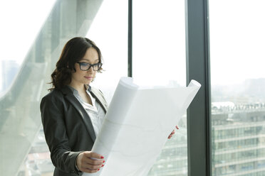 Businesswoman in office looking at blueprint - WESTF019328