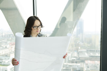 Businesswoman in office looking at blueprint - WESTF019329