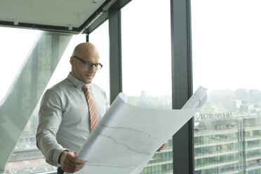 Businessman in office looking at blueprint - WESTF019368