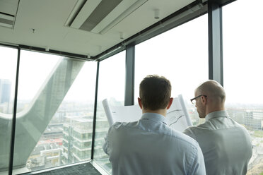 Zwei Geschäftsleute im Büro mit Blick auf einen Bauplan - WESTF019371