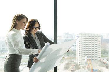 Two businesswomen in office looking at blueprint - WESTF019281