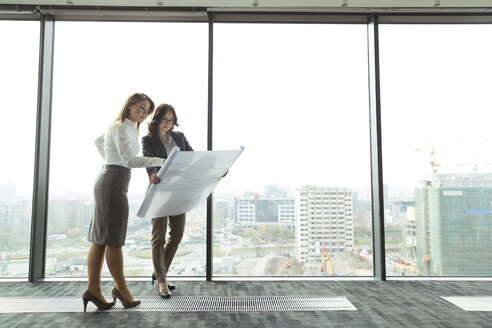 Two businesswomen in office looking at blueprint - WESTF019498