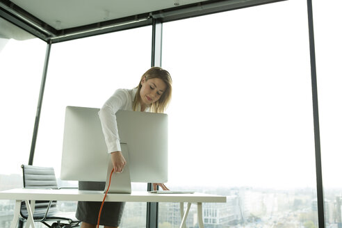 Businesswoman connecting computer monitor - WESTF019293