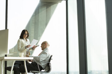 Businessman and businesswoman with documents in office - WESTF019511