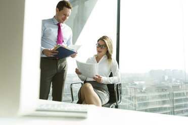 Businessman and businesswoman with documents in office - WESTF019395