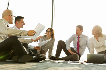 Geschäftsleute sitzen auf dem Boden und besprechen Papiere - WEST019351