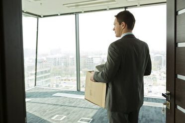 Businessman carrying cardboard box in office - WESTF019434