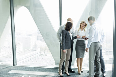 Businesspeople in office with woman using digital tablet - WEST019362