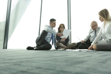Geschäftsleute sitzen auf dem Boden und besprechen Papiere - WEST019442