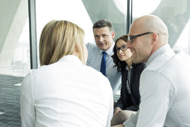 Businesspeople sitting on floor discussing - WEST019448