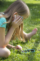 Kleines Mädchen hört Musik mit Smartphone im Garten - YFF000166