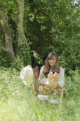 Junge Frau mit digitalem Tablet auf einer Holzbank in einem Garten - LAF000887