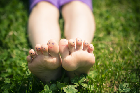 Little girl's feet with painted toes lying in grass stock photo