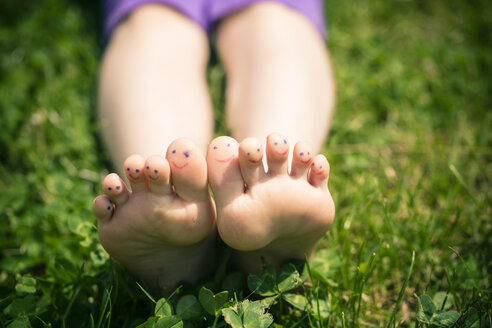 Kleine Mädchenfüße mit bemalten Zehen im Gras liegend - SARF000692