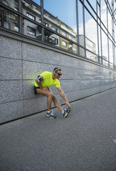 Deutschland, Baden-Württemberg, Mannheim, reife Joggerin beim Stretching in der Stadt - UUF000863