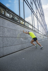 Germany, Baden-Wuerttemberg, Mannheim, mature jogger stretching in the city - UUF000865