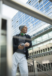 Germany, Baden-Wuerttemberg, Mannheim, athletic mature man with headphones and smartphone - UUF000842