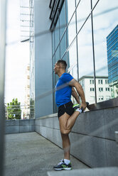 Deutschland, Baden-Württemberg, Mannheim, reife Joggerin beim Stretching in der Stadt - UUF000855