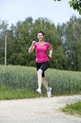 Female jogger running on field path - MAEF008379