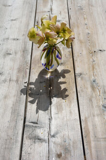 Blumenvase mit Strauß von Winterrosen, Helleborus niger, auf Holz - AXF000691